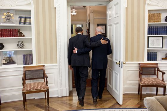 Pres. Obama and VP Biden, President Obama and VP Biden walking through a door with arms around one another's backs.